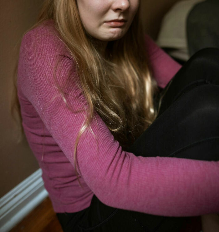 Young woman sitting on the floor looking upset, capturing the challenges of the middle class for Gen Zers today.