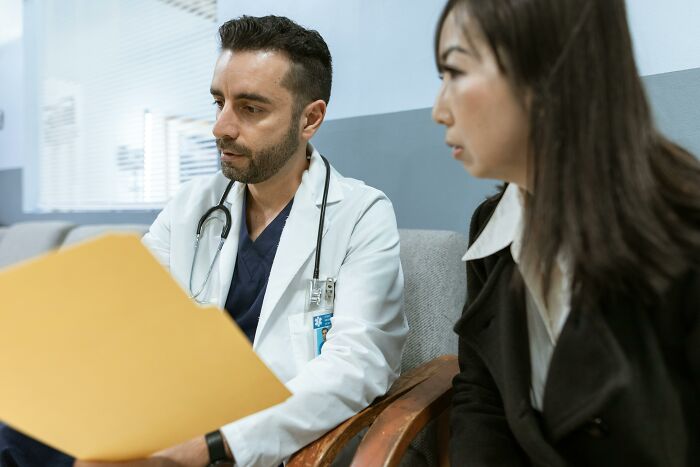Doctor reviewing medical files with patient in a clinic, illustrating cultural differences in healthcare communication.