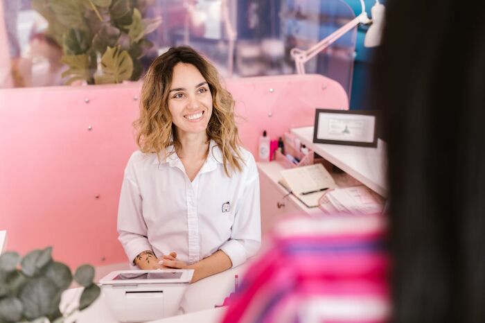 Woman smiling and engaging with a customer at a bright counter, illustrating real-life cheat codes that work effectively.