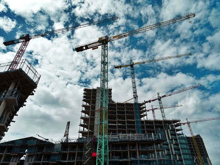 Multiple construction cranes at a building site under a partly cloudy sky, showing appalling facts people unaware.