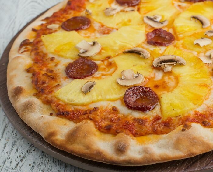 Close-up of a pizza with pineapple, pepperoni, and mushrooms illustrating wild cooking opinions and unique food combinations.