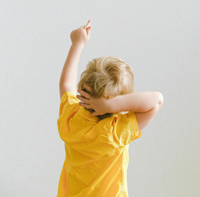 Young student in yellow shirt raising hand, illustrating unhinged teacher strategies that actually work in classroom settings.