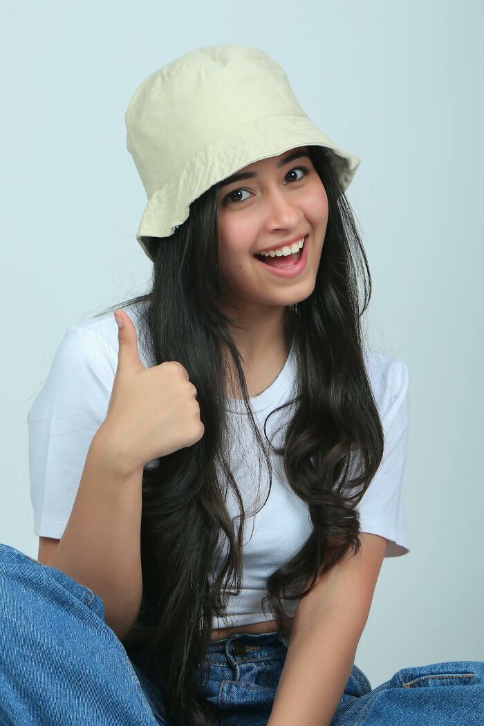 Young woman in casual clothes and a bucket hat smiling and giving a thumbs up about middle class challenges for Gen Z.