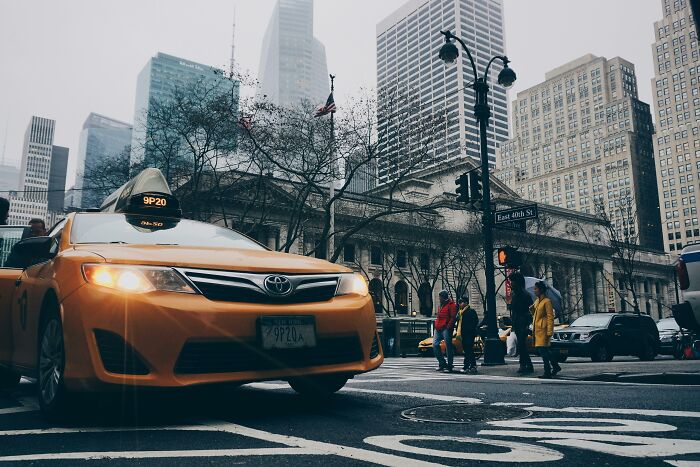 Yellow taxi cab stopping at a busy New York City intersection with skyscrapers and pedestrians around, illustrating out-of-touch moments.