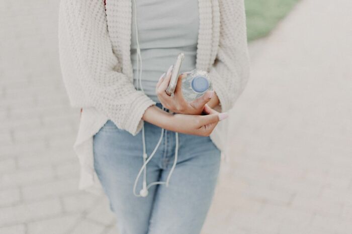 Person in casual outfit holding a phone and water bottle, representing restaurant food consumption trends.