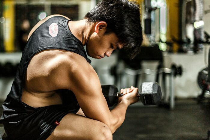 Young man lifting dumbbell in gym, highlighting muscle strength and concerns about Ozempic muscle loss side effects Young man lifting dumbbell in gym, highlighting muscle strength and concerns about Ozempic muscle loss side effects