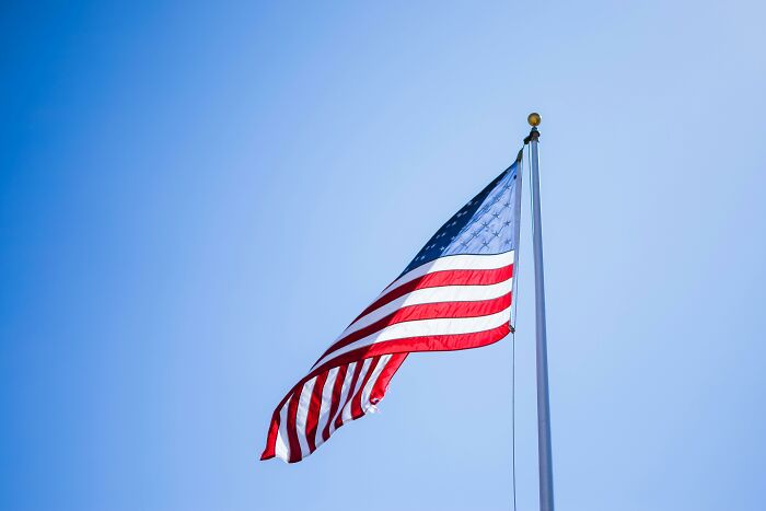 American flag waving on a pole against clear sky, illustrating cultural differences in how people see the world.