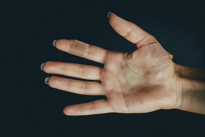 Close-up of a hand with bandages on fingers showing visible body changes that indicate signs of getting older.