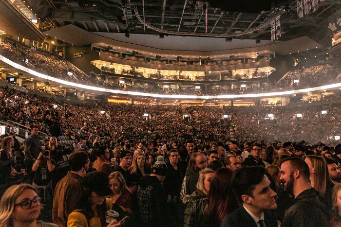 Crowded indoor arena filled with a large diverse audience attending an event, highlighting employee experiences with strange recruiters.