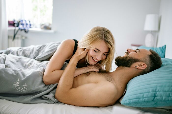 Young couple laughing together in bed, illustrating absurd things people were told growing up they now disagree with.