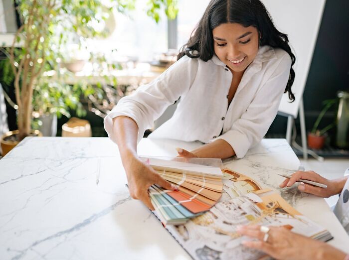 Woman reviewing color swatches at a table, illustrating jobs that shouldn’t be earning as much as they do concept.