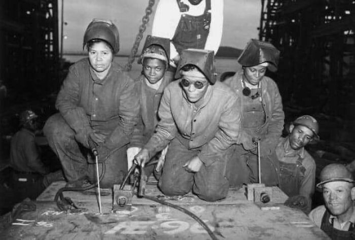 Vintage photo of women workers welding metal in an industrial setting, showcasing history up close during a past era.