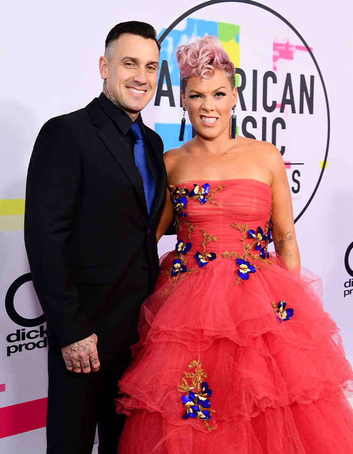 Pink and her husband posing on the red carpet at the American Music Awards, showcasing style and charm.