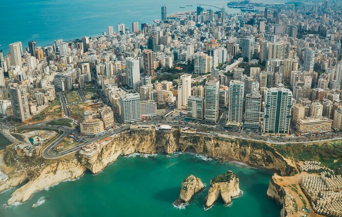 Aerial view of a coastal city with high-rise buildings and rock formations in the sea, a tourist destination once popular.