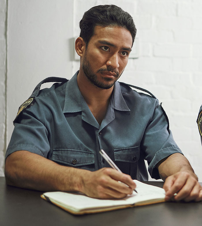 Police officer in uniform taking notes during an investigation about a boyfriend who disappears before a planned vacation.