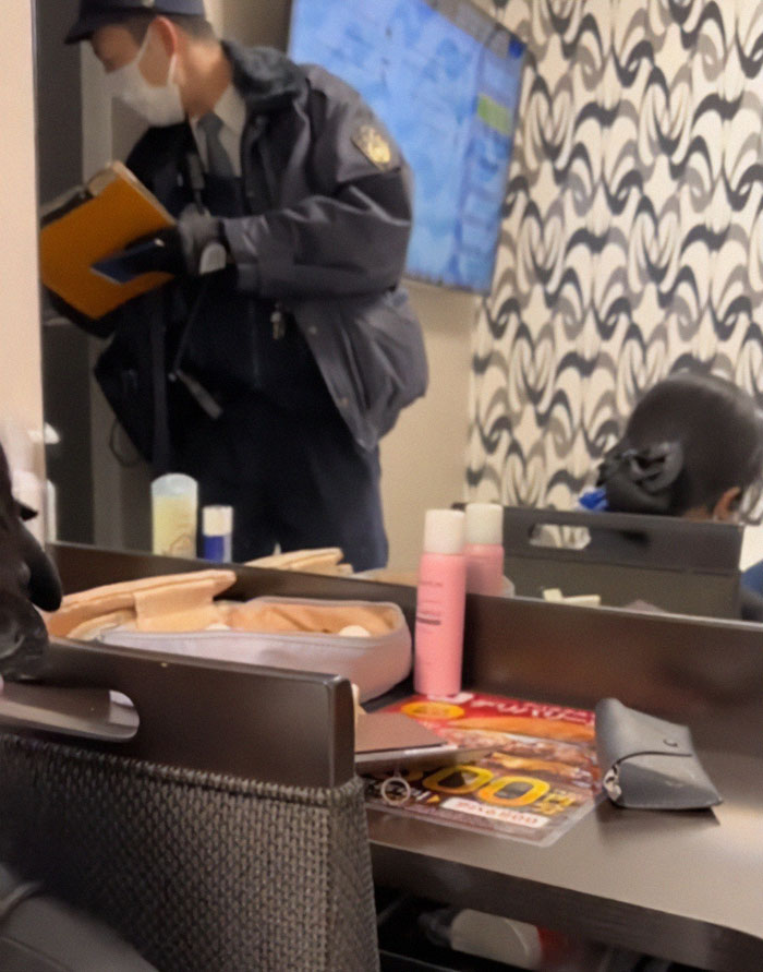 Security officer investigating hotel room with items on desk, related to phrogging and person hiding under bed incident.