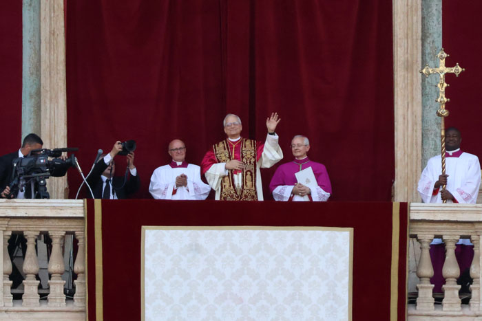 Pope greeting crowd from balcony with clergy in ceremonial robes during Vatican event on permitted white outfits for women.