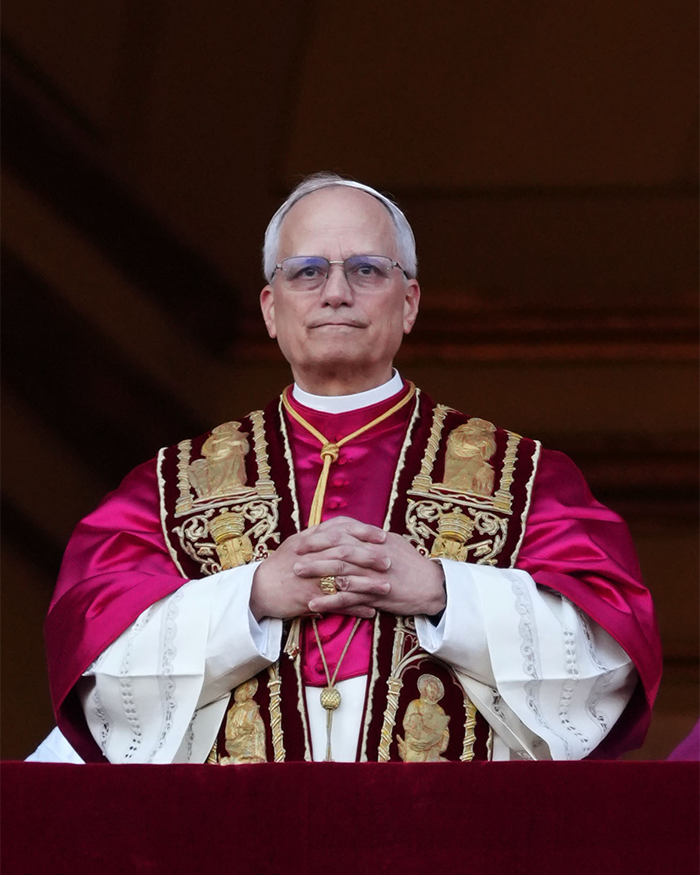 A pope wearing ornate robes and glasses, delivering a menacing message to the United States at a public event.