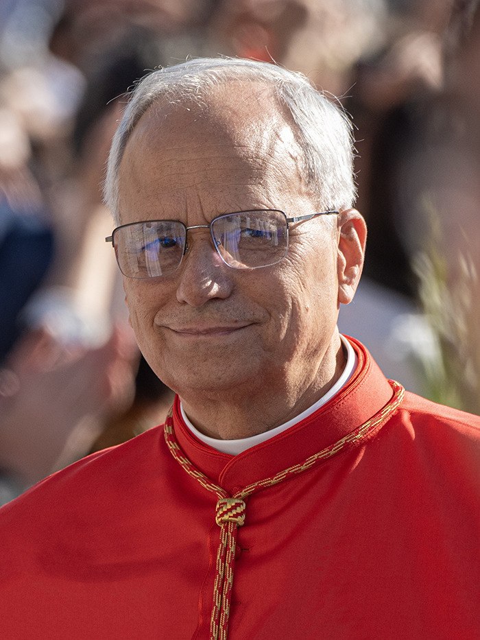 Close-up of a religious leader wearing glasses and a red robe, reflecting the menacing message from the Pope.