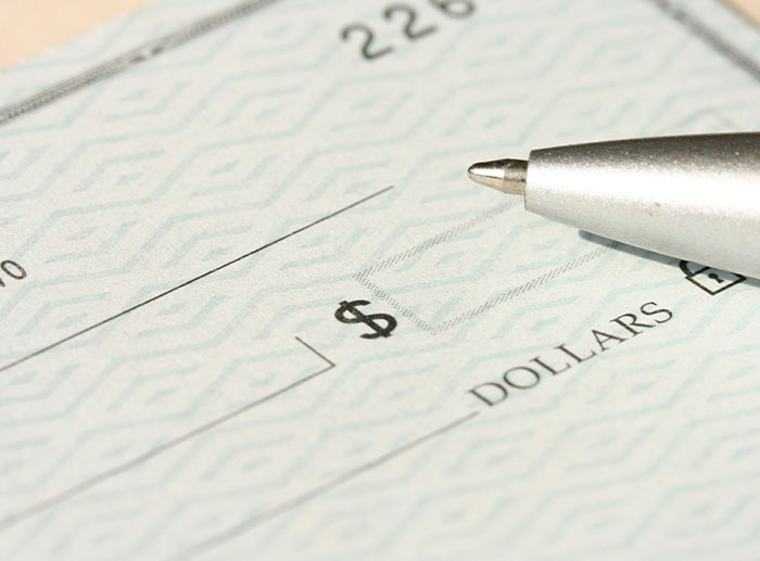 Close-up of a blank check and silver pen illustrating corporate and PR disasters related to financial or business errors.