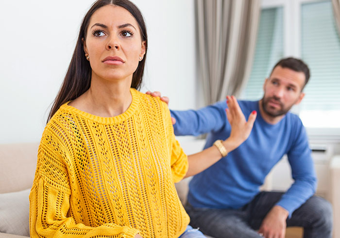 Woman in yellow sweater rejecting man in blue shirt during a tense moment, illustrating gaslighting in a troubled marriage.
