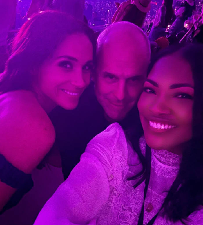 Three people smiling at a concert with purple lighting, highlighting hidden symbols on Prince Harry’s cowboy hat. Three people smiling at a concert with purple lighting, highlighting hidden symbols on Prince Harry’s cowboy hat.