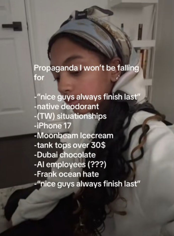 Person wearing a headscarf reading a list of propaganda they refuse to fall for in a casual indoor setting.