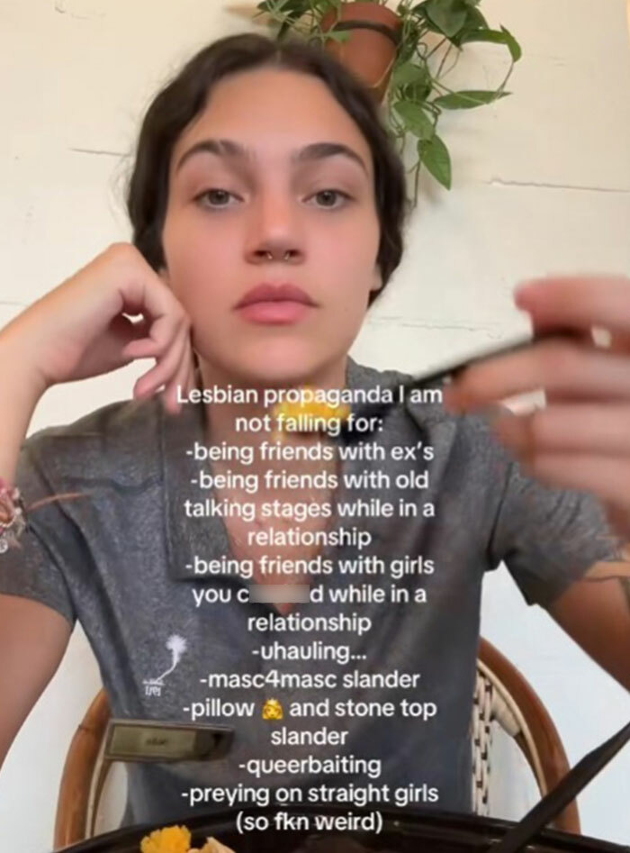 Young person sharing thoughts on propaganda they refuse to fall for, seated indoors with a plant in the background.