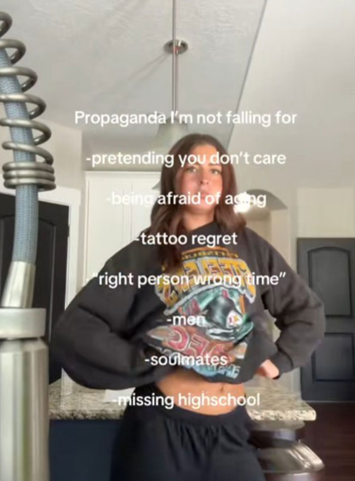 Young woman in casual clothes listing types of propaganda she refuses to fall for in a modern kitchen setting.