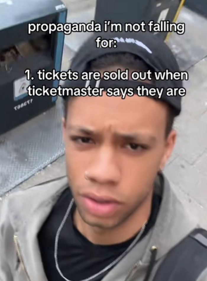 Young man wearing a black cap and jacket sharing propaganda he refuses to fall for about sold-out tickets.