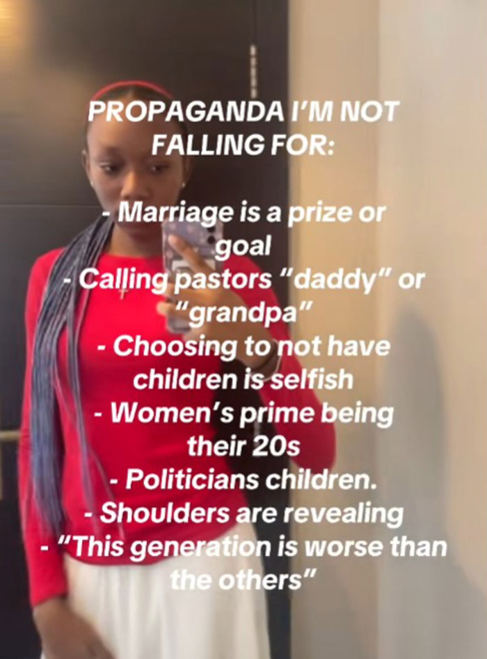 Young woman in red top sharing propaganda beliefs she refuses to fall for with text overlay on mirror selfie