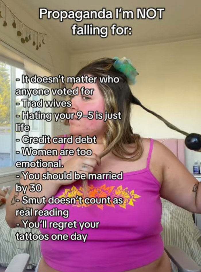 A woman in a pink top curling her hair with text listing propaganda she refuses to fall for, including credit card debt and emotional stereotypes.