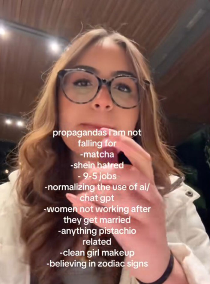 Young woman wearing glasses shares list of propaganda she refuses to fall for, including AI normalization and 9-5 jobs.