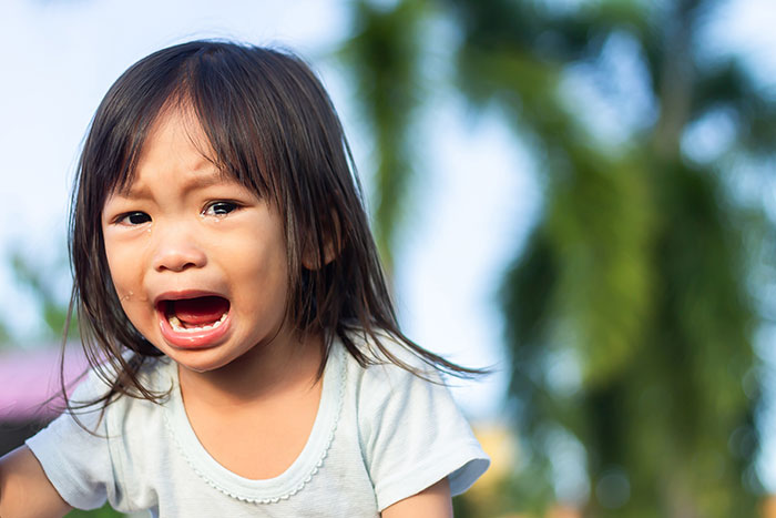 Crying child outdoors illustrating emotional pain from siblings of narcissists and sociopaths in family relationships.