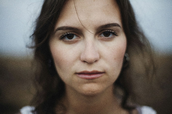 Close-up of a serious young woman outside, reflecting the pain of siblings of narcissists and sociopaths.