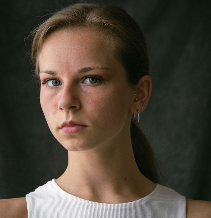 Young woman with serious expression, representing siblings of narcissists and sociopaths facing emotional struggles.