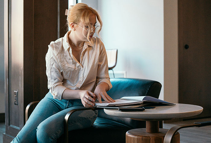 Young woman reading and writing notes on a notebook, reflecting on heartbreaking stories of siblings of narcissists.