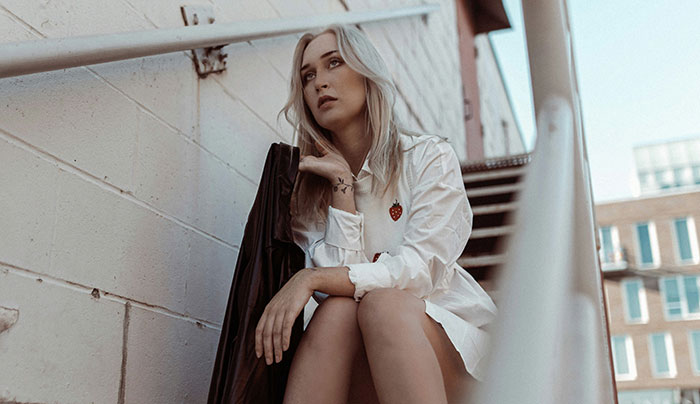 Young woman sitting on outdoor stairs looking thoughtful, reflecting on siblings of narcissists and sociopaths.
