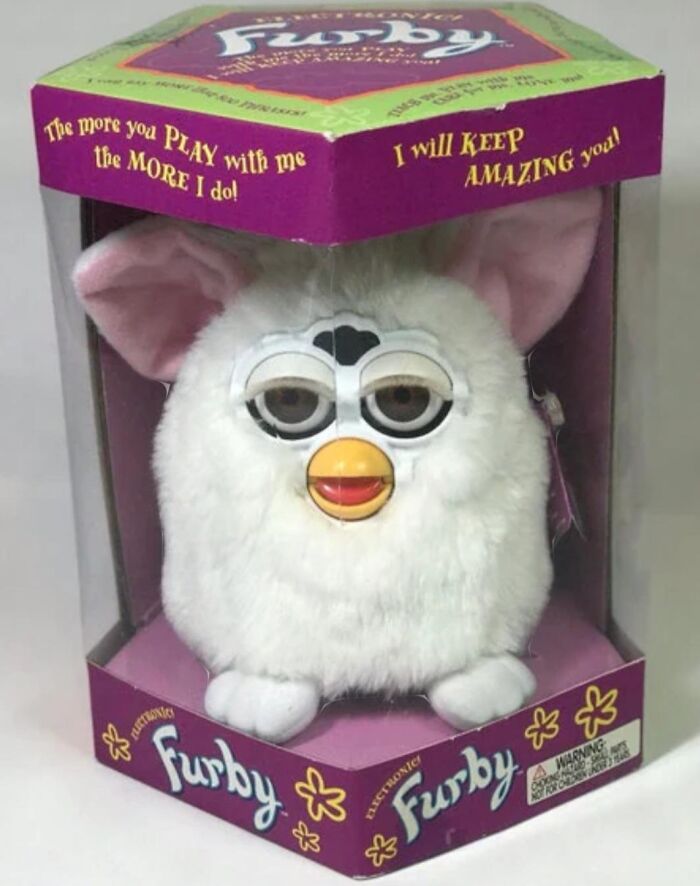 White Furby toy in original purple box, an iconic cringey nineties fashion and childhood collectible.