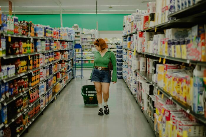 Woman shopping in a grocery store aisle, illustrating microfeminisms women use to support women and annoy men.