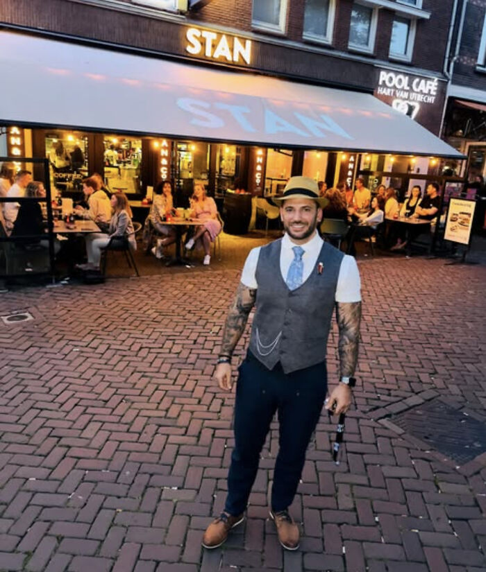 Man with tattoos wearing vest and hat standing outside Stan cafe with diners in the background, Harry Potter star Viktor Krum news.