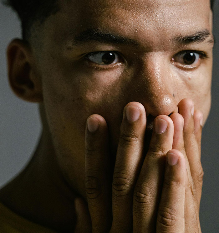 Close-up of a man covering his mouth with hands, showing a shocked expression about the wind made by trees concept.