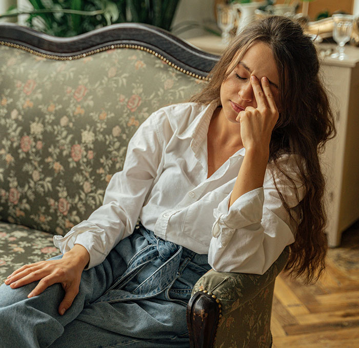 Woman sitting on floral couch looking frustrated, illustrating hilarious moments people realized their partner wasn’t the brightest.