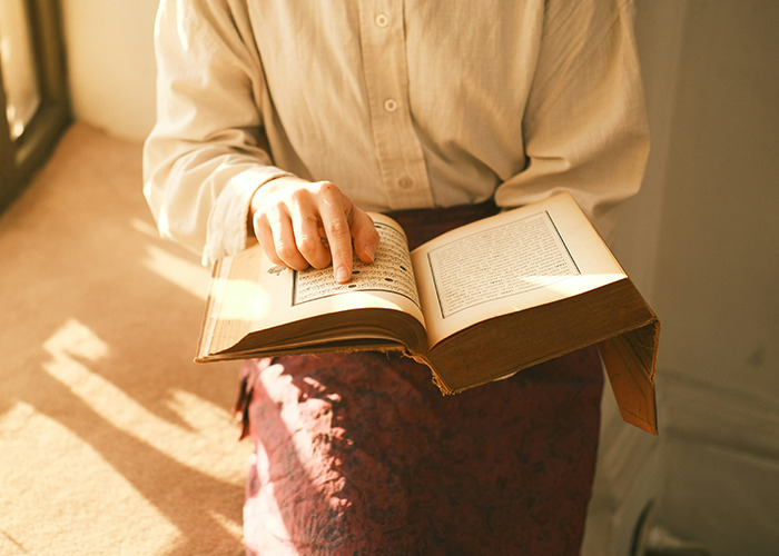 Person wearing a white shirt reading an old book, illustrating raw stories of parents disowning their kids.