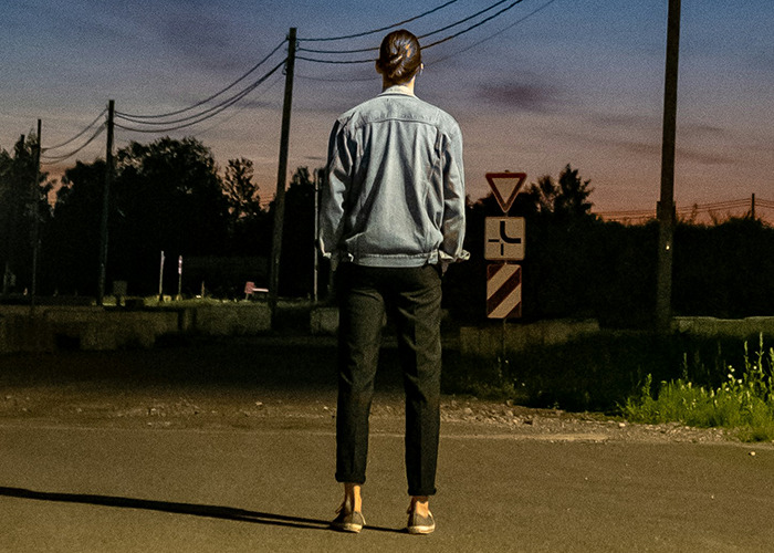 Person standing alone at dusk on an empty street, reflecting themes of parents disowning their kids and family struggles.