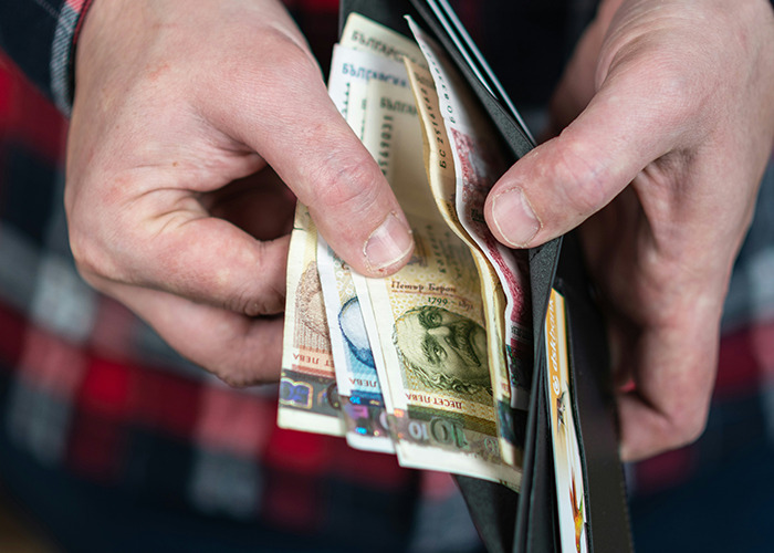 Hands holding a wallet with various bills, illustrating financial struggles in stories of parents disowning their kids.