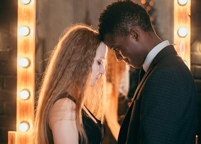 A young couple gently touching foreheads, reflecting complex emotions about parents disowning their kids.