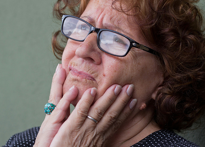 Elderly woman with glasses looking sad and reflective, symbolizing raw stories of parents disowning their kids.