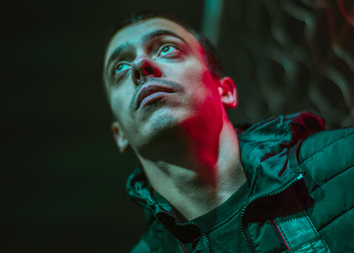 Young man looking up with a somber expression, illustrating raw stories of parents disowning their kids in a dark setting.