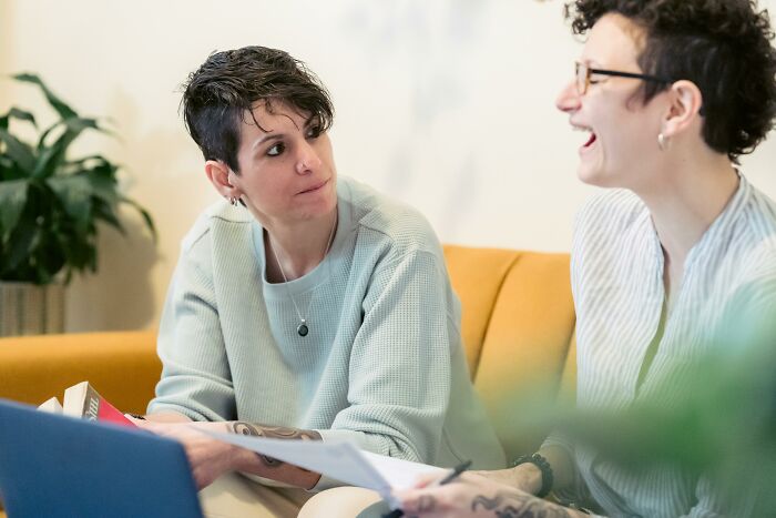 Two people discussing paperwork on a yellow couch in a casual setting during a Red Flag Poll session.